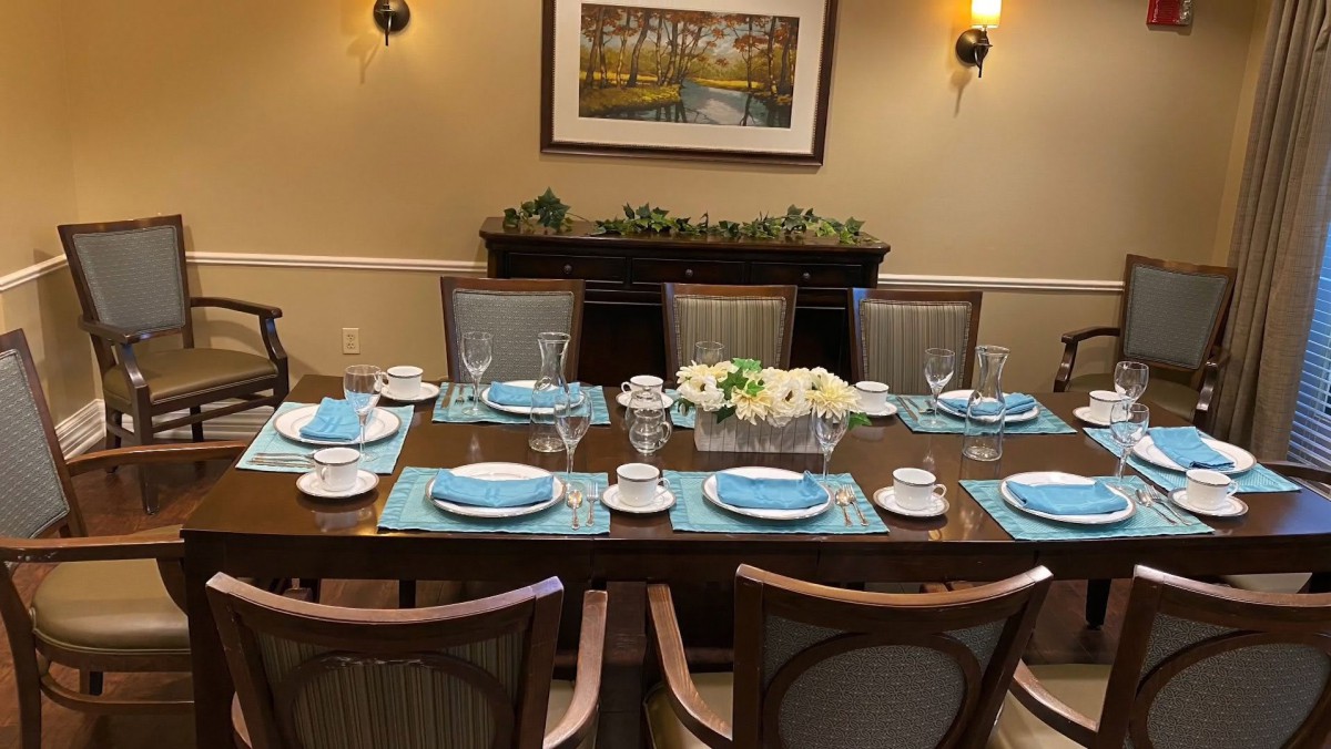 A neatly set dining table with blue placemats and white floral centerpiece.
