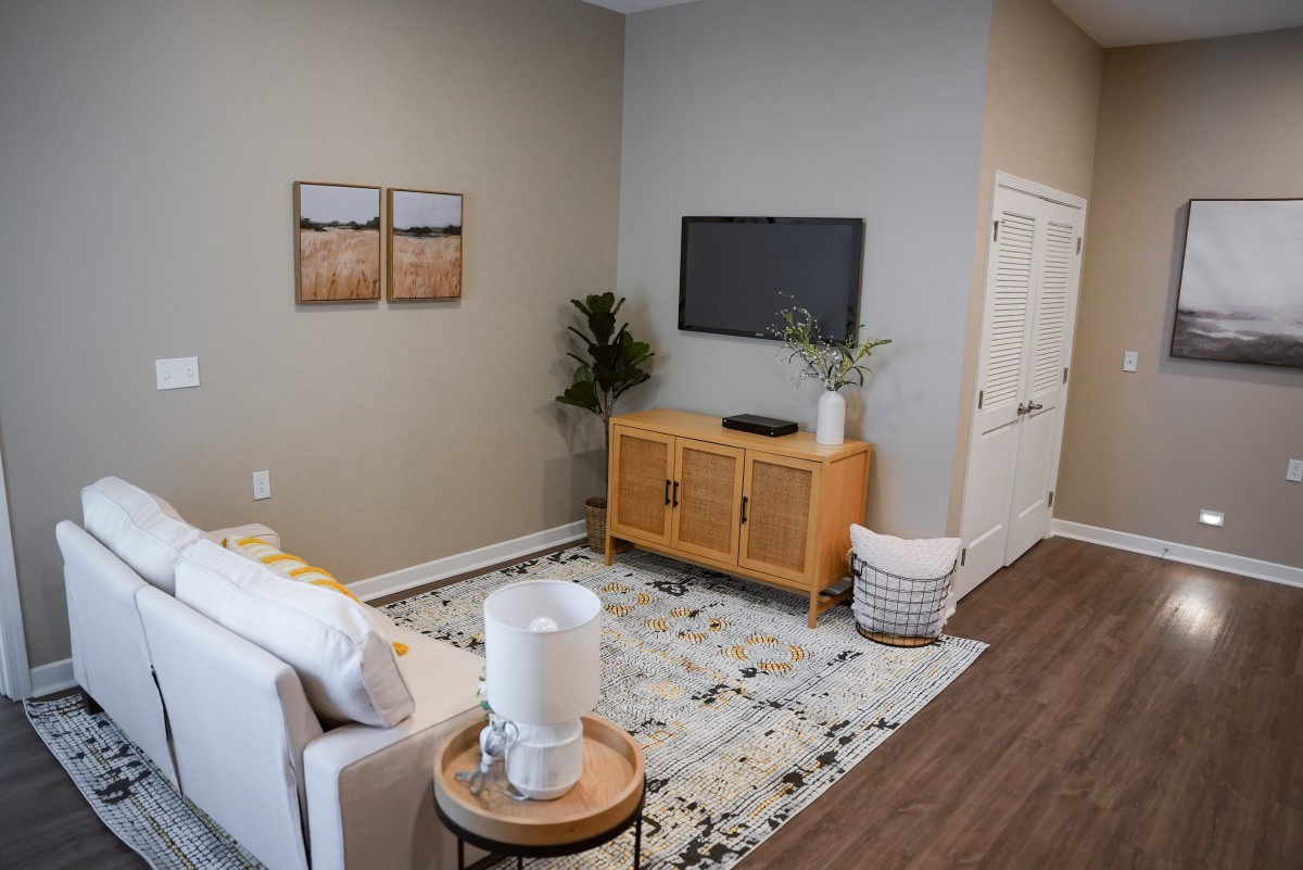 A modern and minimalist living room with a cozy seating area, wall-mounted TV, and stylish decor.