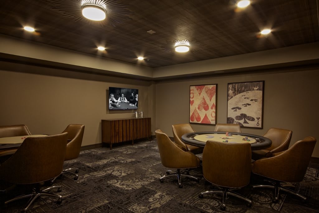 A modern conference room featuring a round table surrounded by chairs, with a television and artistic wall decorations.