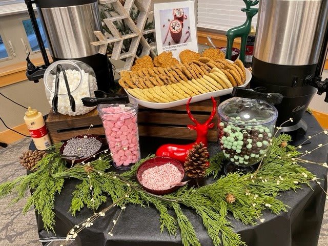 A festive display featuring cookies and candy surrounded by holiday greenery.
