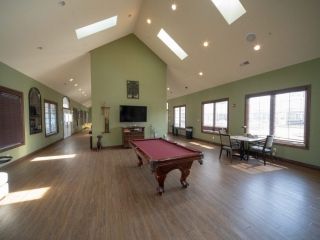A spacious room featuring a pool table, vaulted ceilings with skylights, and large windows providing ample natural light.