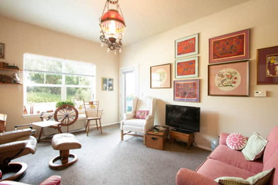 A cozy living room with comfortable seating, a TV, and colorful decorations.