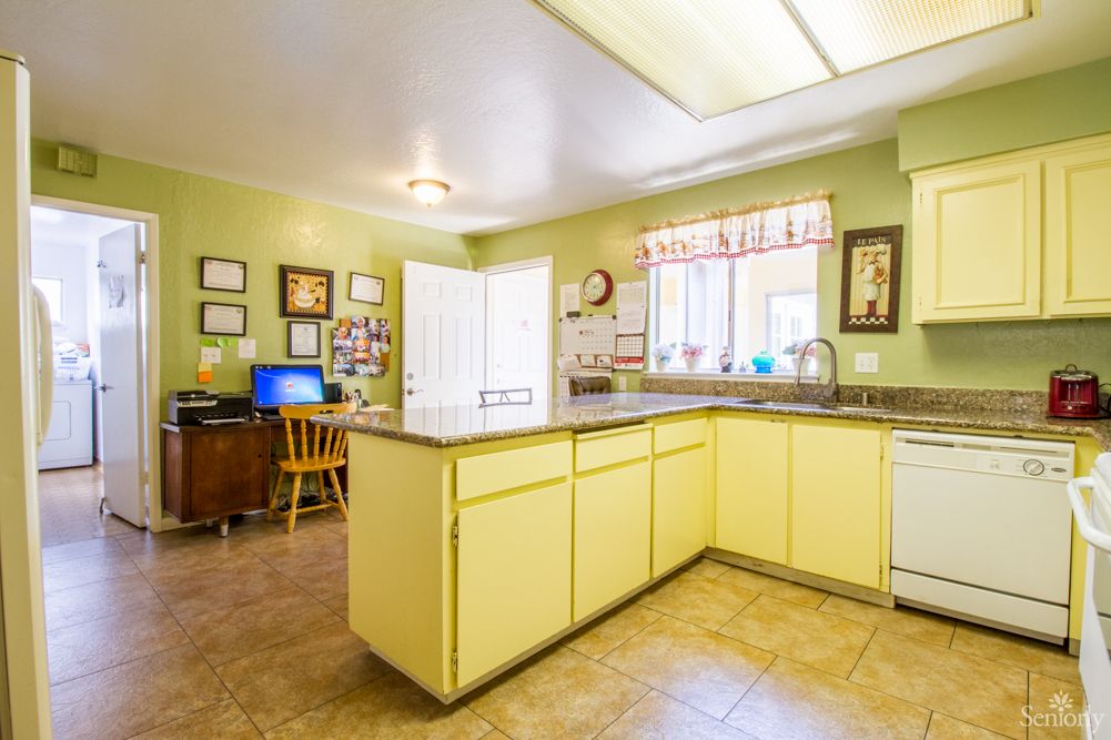 A bright kitchen with yellow cabinets and a central island, featuring a homey decor and ample natural light.