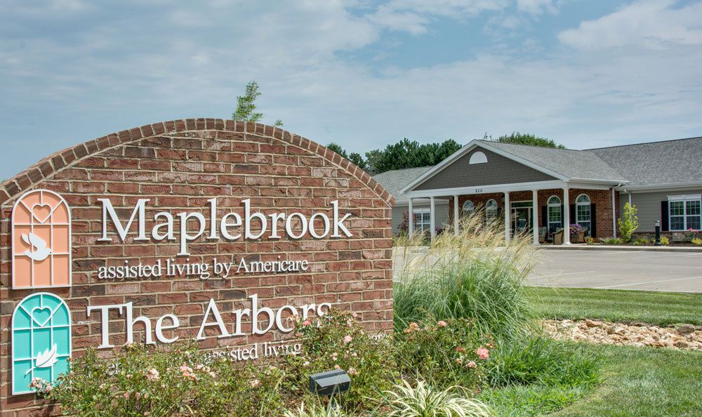 A brick sign in front of a retirement community building on a clear day.