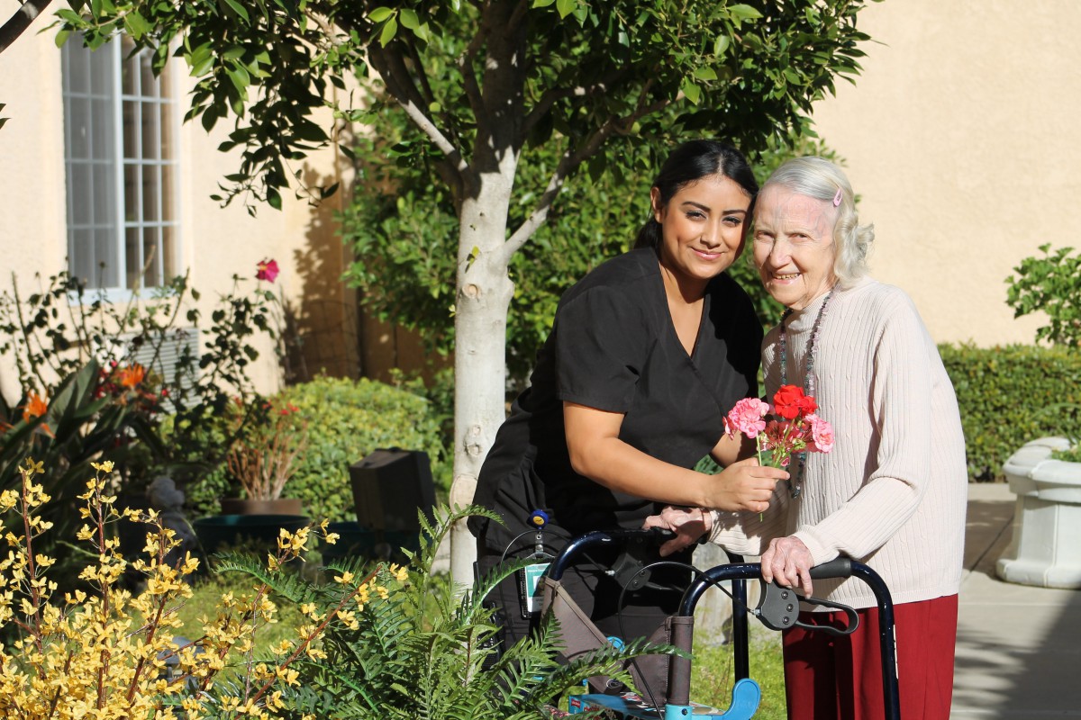 A caregiver and an elderly woman enjoying time together in the garden.