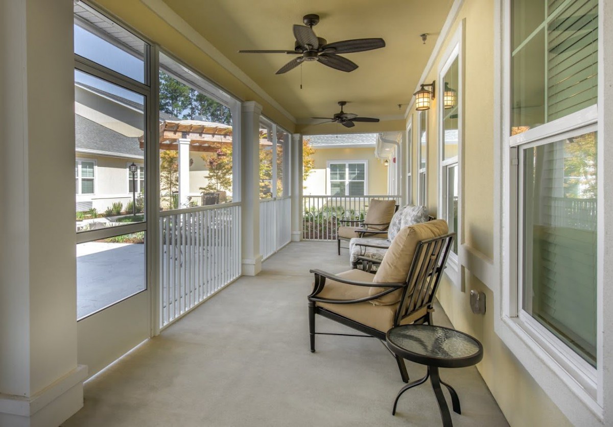 A cozy porch with comfortable seating and ceiling fans, perfect for relaxing outdoors.