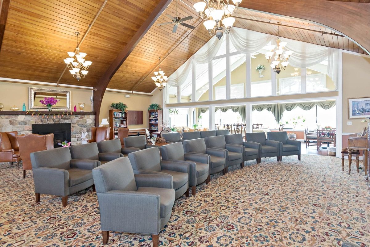 A spacious lounge area featuring rows of comfortable chairs, large windows, and elegant chandeliers.