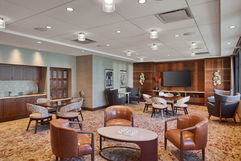 A modern lounge area featuring comfortable seating and a large screen, designed for meetings and relaxation.