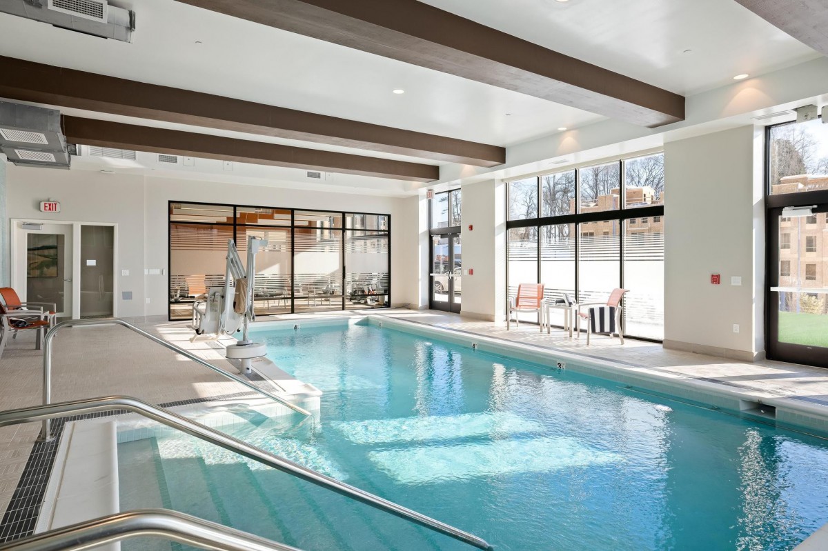 A bright and modern indoor swimming pool with large windows allowing natural light to flood the space.
