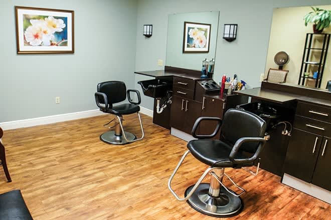 A cozy hair salon with stylish chairs and mirrors on a wooden floor.