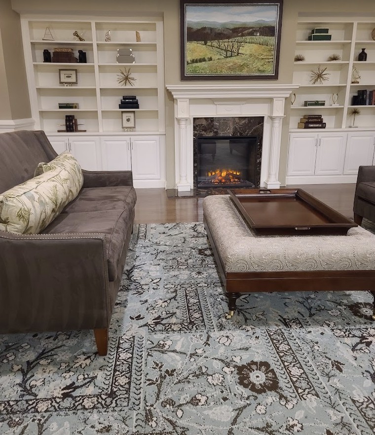A cozy living room with a sofa, armchair, and a warm fireplace.