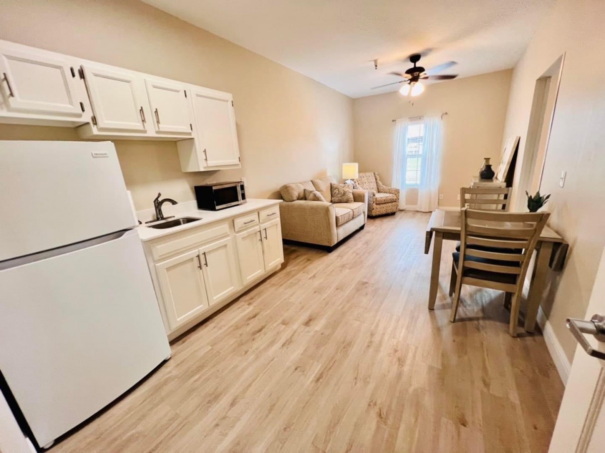A cozy, open-plan living space featuring a kitchen, dining area, and lounge with wood flooring.