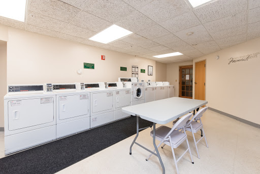 A clean and organized laundry room equipped with washing machines and dryers, along with a table and chairs for convenience.