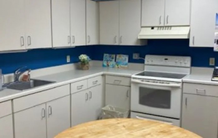 A modern kitchen with white cabinets, a stove, and a blue accent wall.