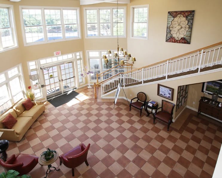 A spacious lobby with a chandelier, checkered flooring, and comfortable seating.