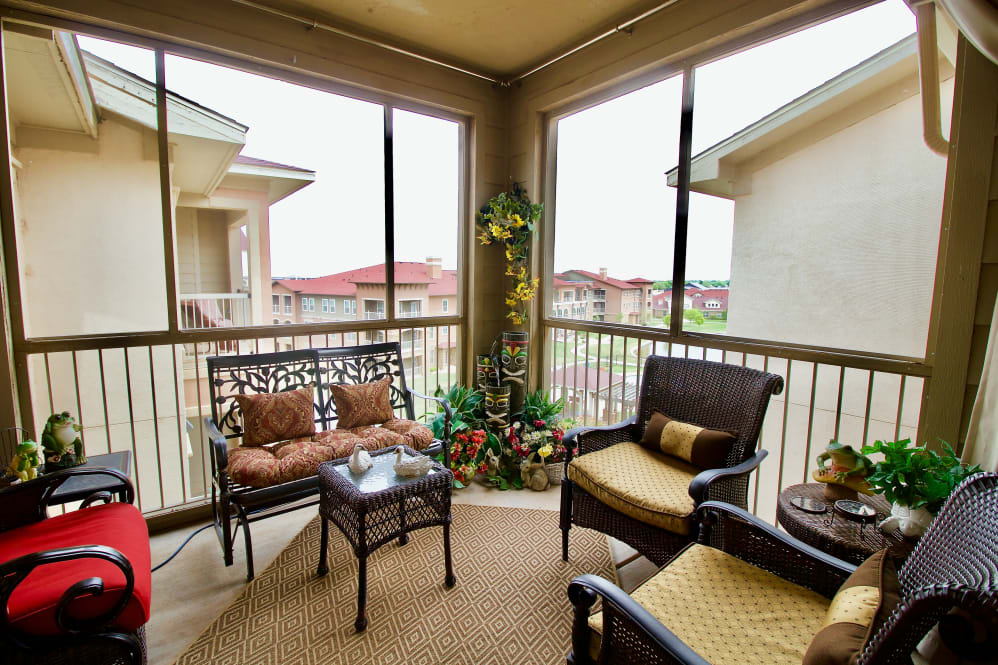A cozy balcony with comfortable seating and decorative plants, overlooking neighboring buildings.