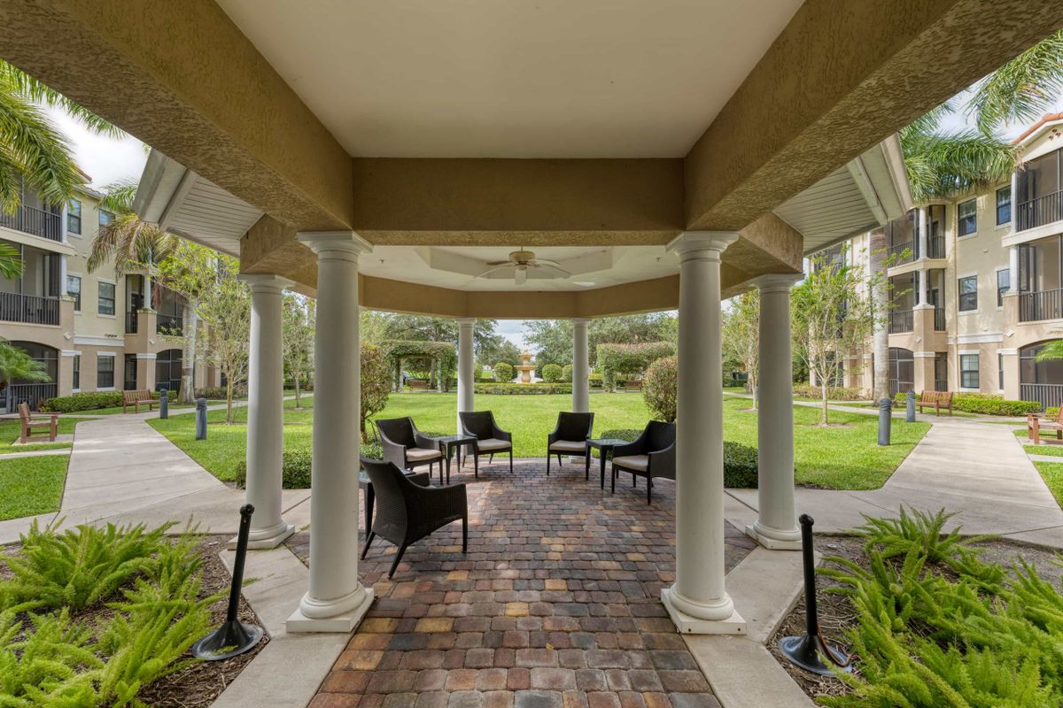 A covered patio with columns and outdoor seating overlooking a garden.