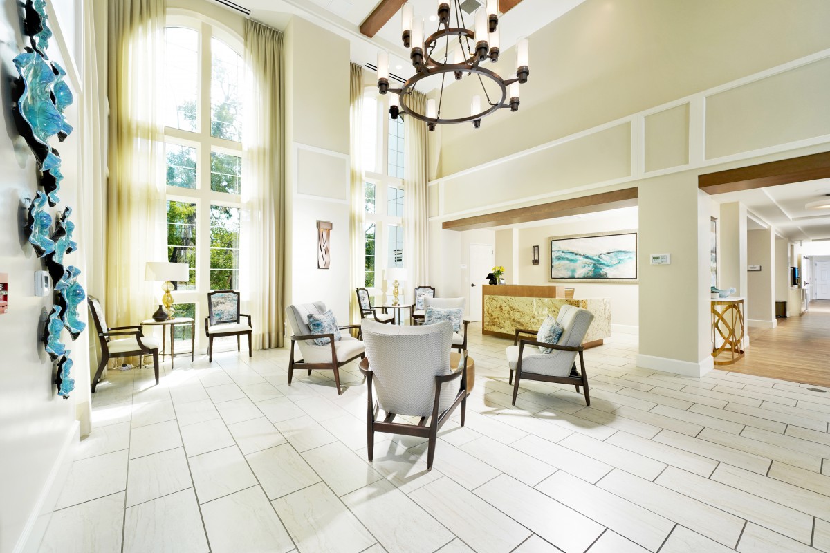 A spacious and elegantly designed lobby area featuring comfortable seating, a grand chandelier, and abundant natural light.