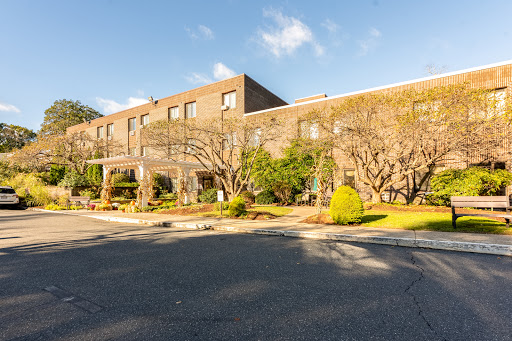 A modern building surrounded by lush greenery and a clear blue sky.