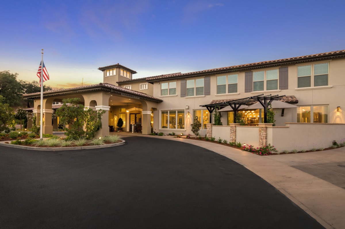 A large residential house with a well-maintained exterior and spacious driveway, photographed at twilight.