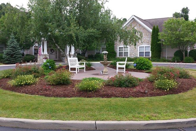 A landscaped garden with a patio area featuring outdoor chairs and surrounded by greenery.