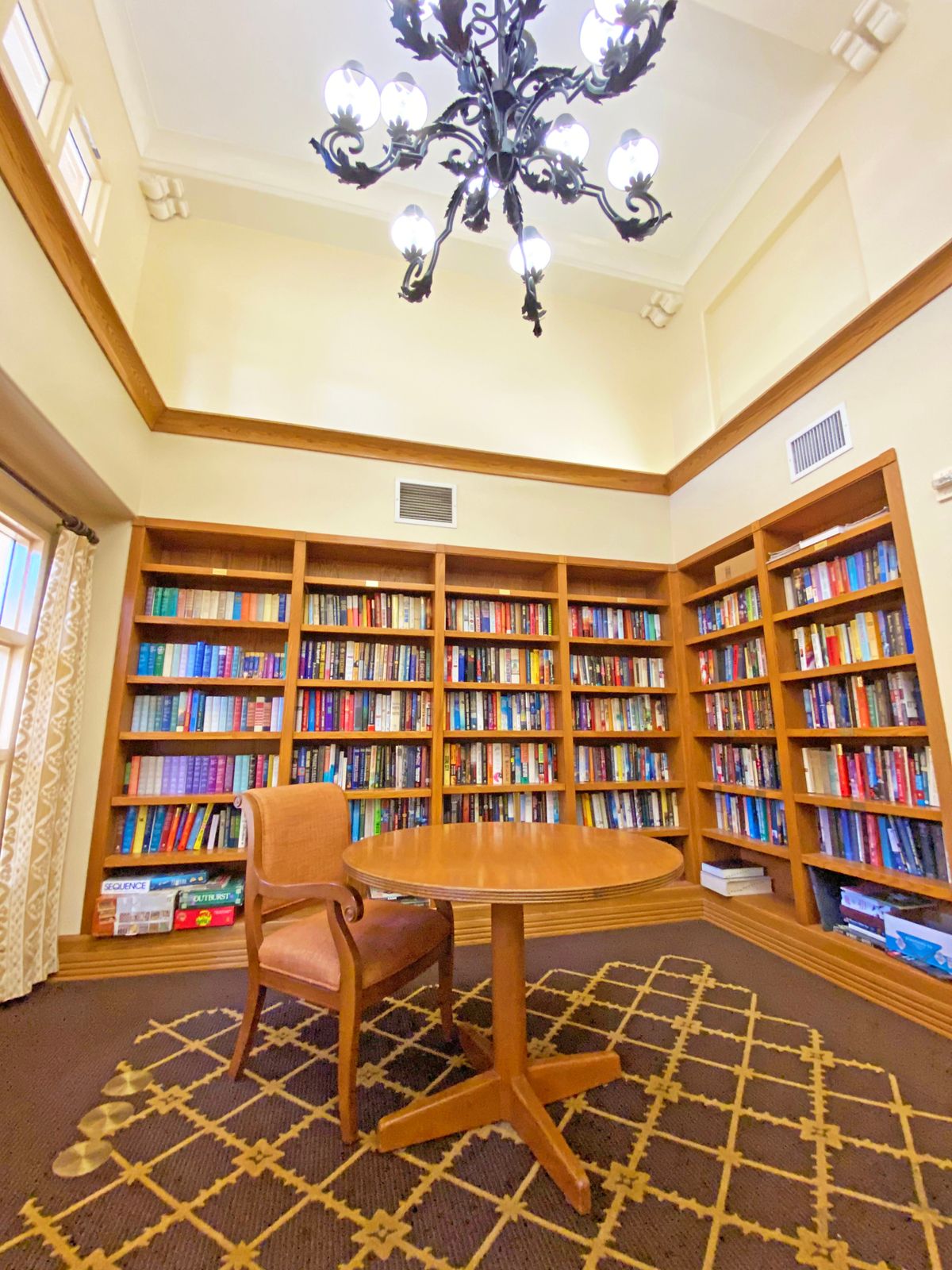 A cozy library corner with wooden bookshelves, a round table, and a comfortable chair.