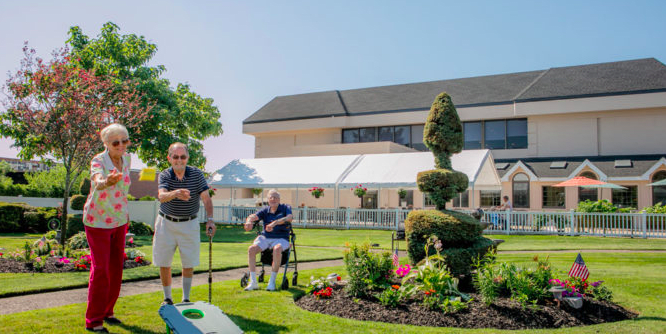 A sunny day in the garden with people enjoying leisure activities near a topiary.