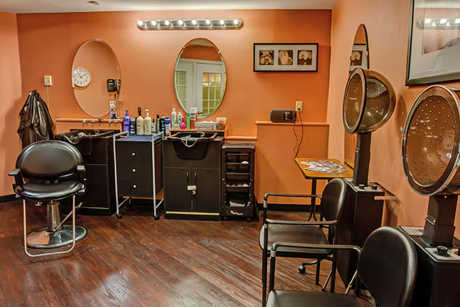 A cozy hair salon interior featuring styling stations with mirrors and chairs, surrounded by a collection of hair care products.