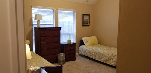 A cozy bedroom featuring a single bed, dresser, and natural light from the windows.