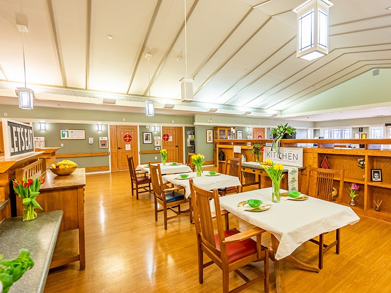 A well-lit dining area with neatly arranged tables and decorative plants.