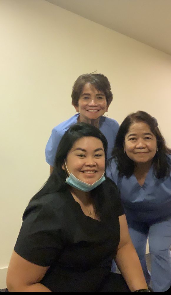 A group of women smiling together, two wearing scrubs.