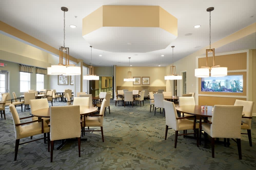A modern dining area with neatly arranged tables and chairs, featuring elegant lighting.