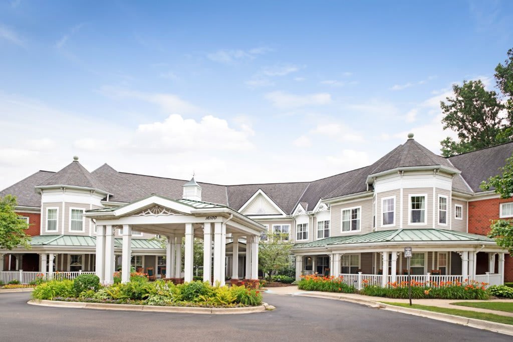 A large residential building with white columns and landscaped grounds under a blue sky.