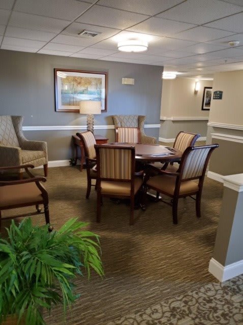 A cozy lobby area with a table and chairs, adorned with artwork and lighting.