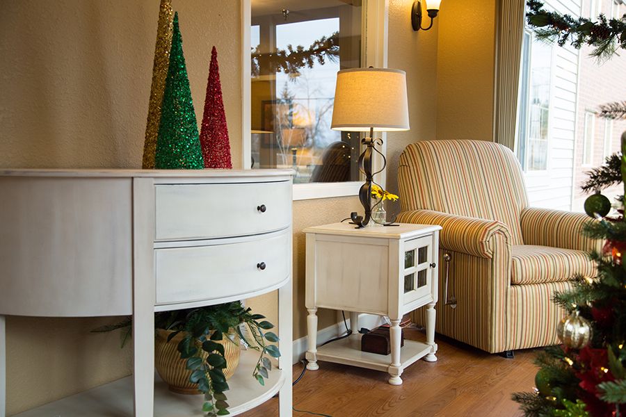 Cozy living room corner with a lamp, armchair, and holiday decorations.