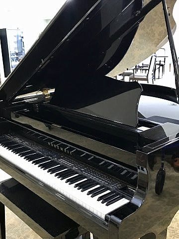 A grand piano with its lid open, showcasing the keyboard.