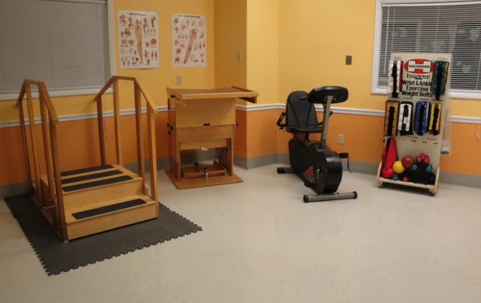 A rehabilitation room equipped with therapy equipment including an exercise bike and stairs.