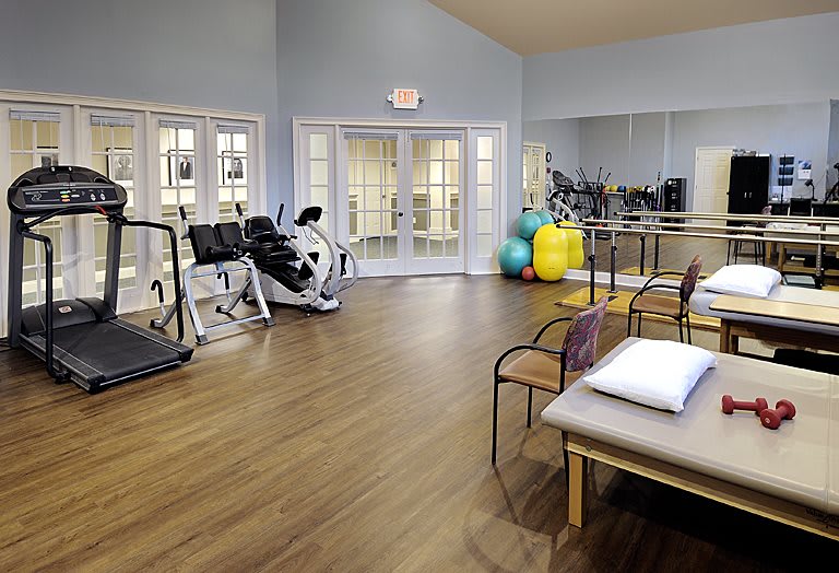 A spacious fitness area equipped with various exercise machines and physical therapy tools.
