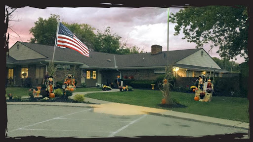 A beautifully landscaped residence with autumn decorations and an American flag waving in the breeze.