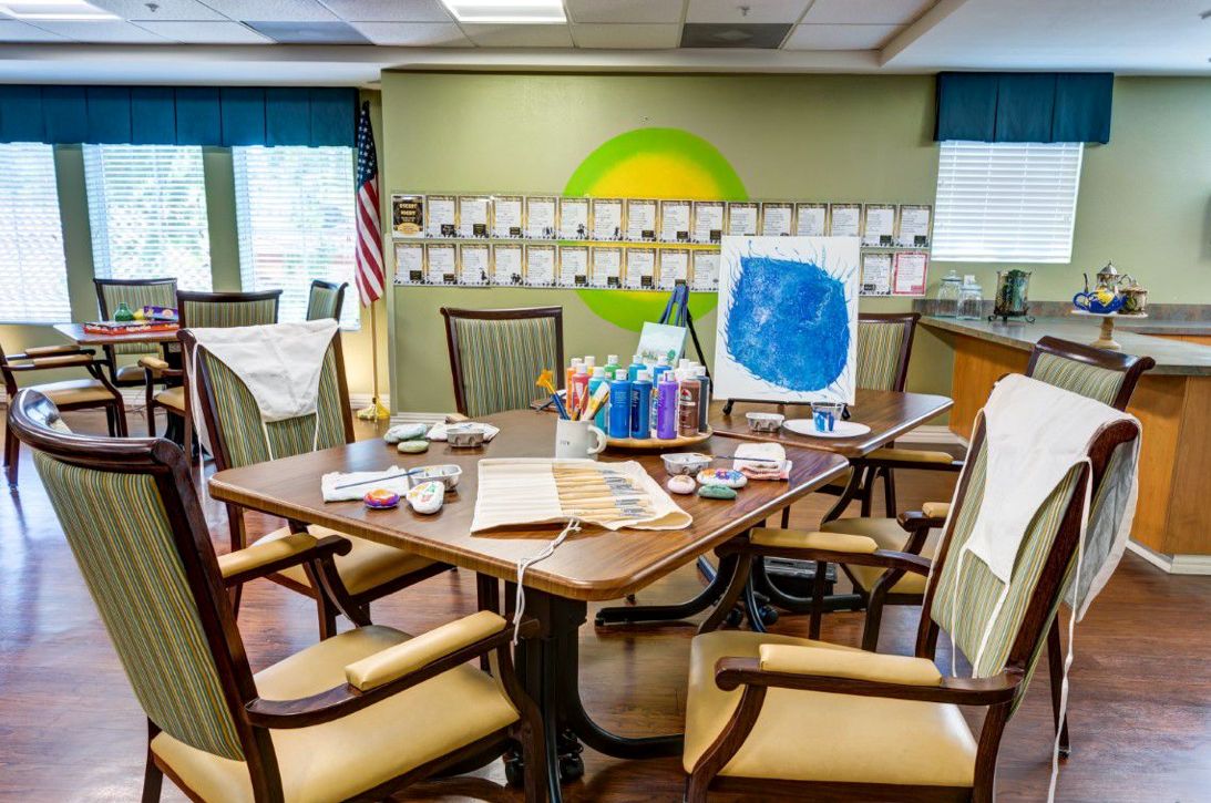A creative craft room with art supplies and paintings on display, featuring a table surrounded by chairs.