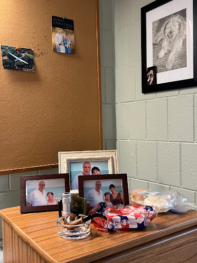 A cozy corner of an office space featuring family photos, decorative items, and a bulletin board.