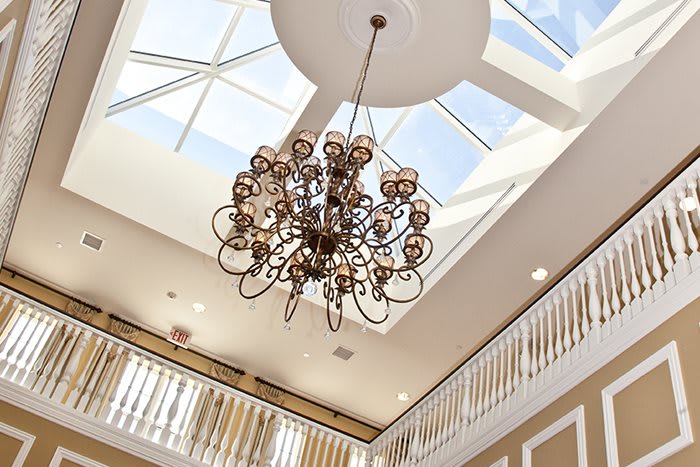 A luxurious chandelier hanging from a ceiling with a skylight above.
