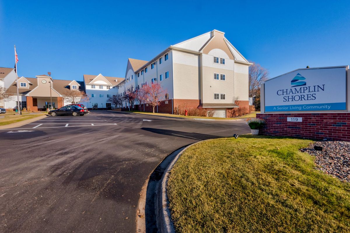 Exterior view of a hotel with a parking lot under a clear blue sky.