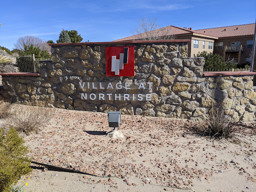 Entrance sign for the Villages at Northrise, featuring a stone wall and clear blue sky.