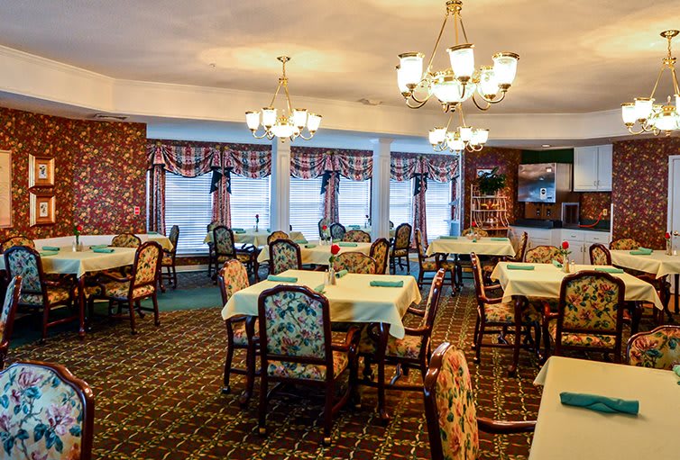 A cozy dining room with elegant chandeliers and decorated tables.