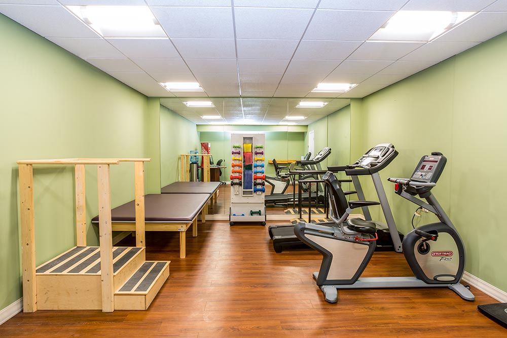 A gym room equipped with treadmills, a stationary bike, and various workout equipment.
