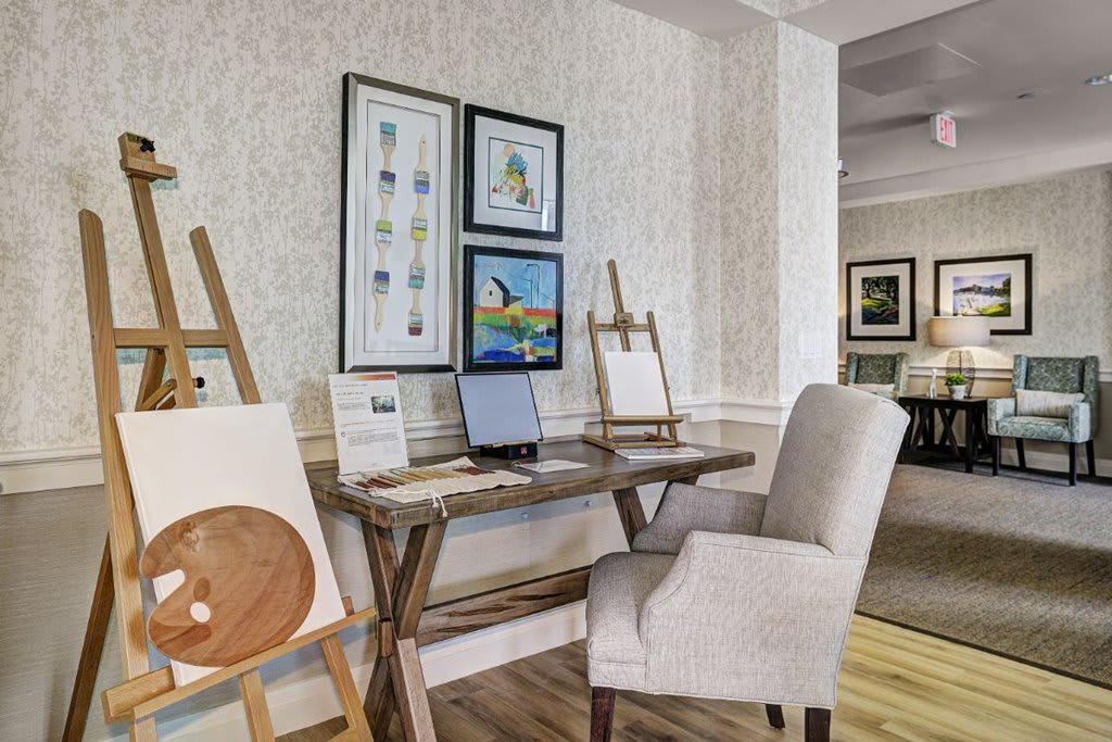 A cozy art studio with easels, paintings, and a comfortable chair.