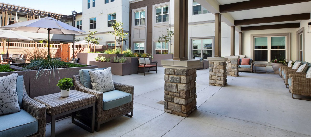A modern patio area with comfortable seating and landscaped planters, surrounded by building exteriors.