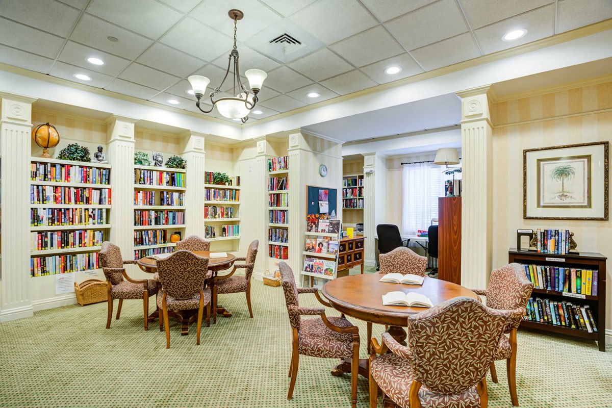 A cozy library interior with bookshelves, tables, and chairs for reading.