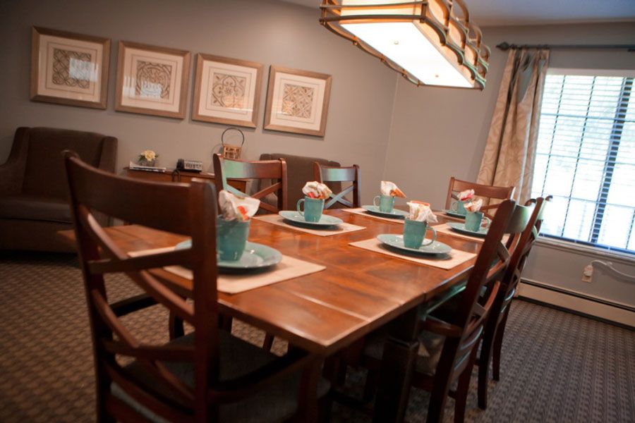 A well-decorated dining room features a wooden table set with turquoise dinnerware and floral arrangements, under a stylish lighting fixture.